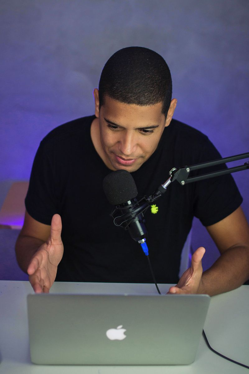 African American man hosts a podcast in a home studio using a microphone and laptop.